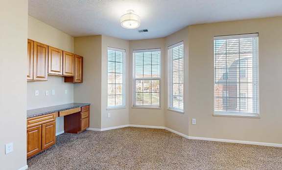 a living room with a bay window and built-in desk, providing a bright and functional workspace