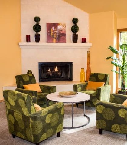 a living room with green chairs and a fireplace at King's Court Apartments, Beaverton, 97006