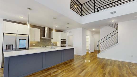 A modern kitchen with wooden floors and a staircase.