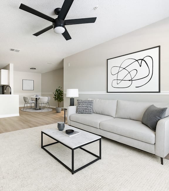 A living room with a white couch, a coffee table, and a ceiling fan.