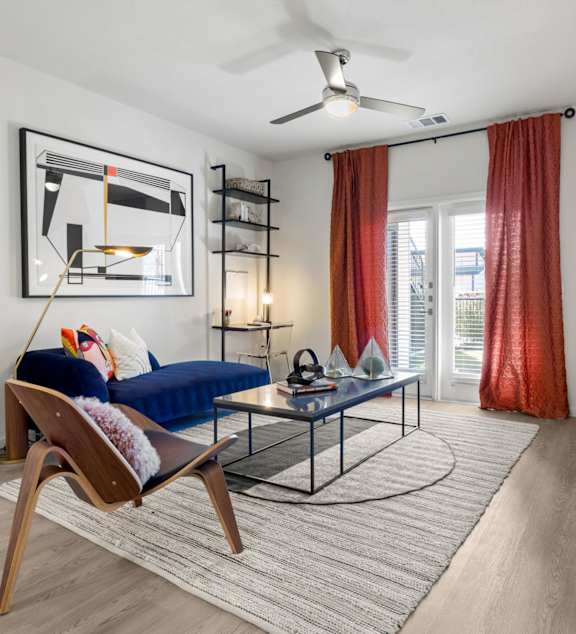 A living room with a blue sofa and a wooden chair. at Bridge at Tech Crossing, Austin