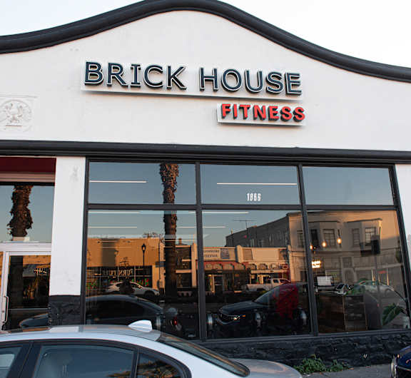 A white building with a red door and a sign that says Brick House Fitness.