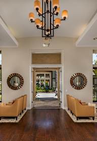 A large, well-lit room with a chandelier, sofas, and mirrors.