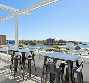 Rooftop terrace with lounge seating, high-top tables, and waterfront views at The Constellation on King