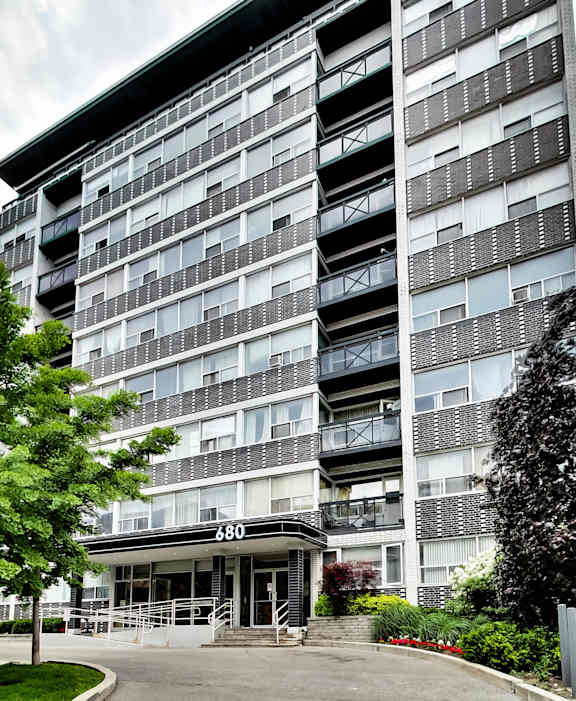 an apartment building with a driveway and trees in front of it