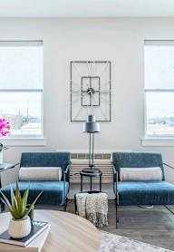 A living room with a sofa, two chairs, a coffee table, and a potted plant.