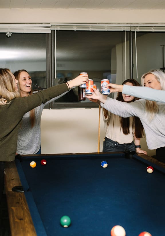 a group of girls making a toast over a pool table