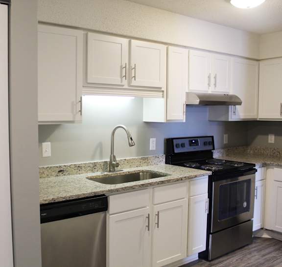 A kitchen with white cabinets and a black stove top oven at The Avery at Auburn Apartments in Auburn, AL