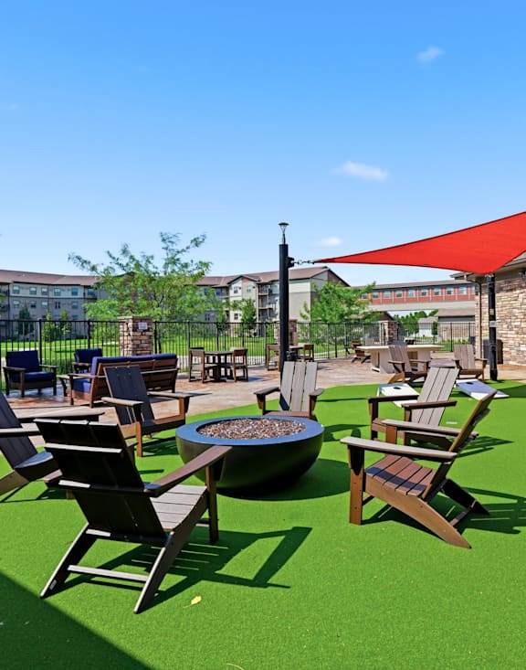 A patio with a fire pit and chairs.