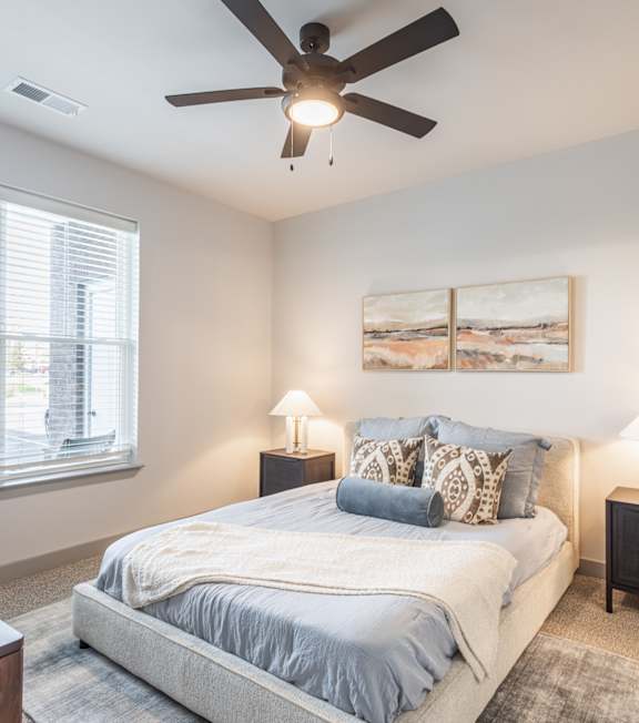 A bedroom with a bed, two lamps, and a painting on the wall. at Viridian Apartments LLC Apartments, Kentucky