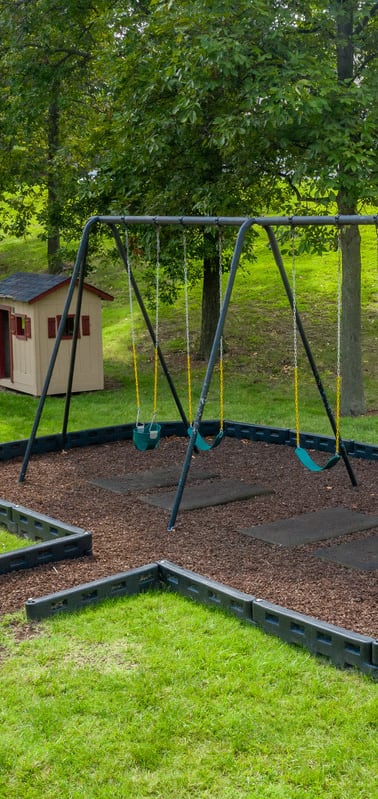 a swing set in a park with a bird house