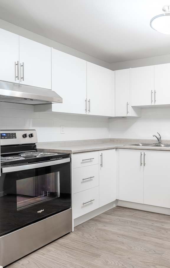 A modern kitchen with white cabinets and stainless steel appliances.