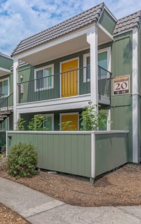 a row of green houses with yellow doors and a sidewalk at Napa Green Apartments LLC, Napa, CA