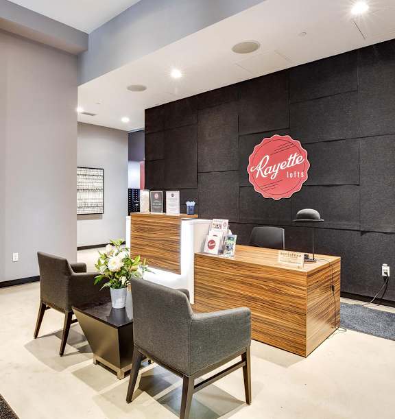A reception area with a wooden desk and chairs, a potted plant, and pictures on the wall.