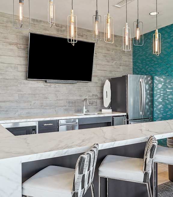 A modern kitchen with a marble countertop and a TV mounted above it.
