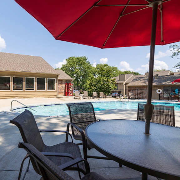 A crystal-clear swimming pool with a sun deck and shaded seating.