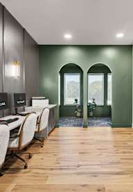 A conference room with a green wall and a white table.