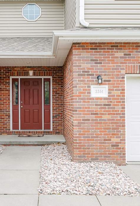 A red door is on the left side of a white garage door.