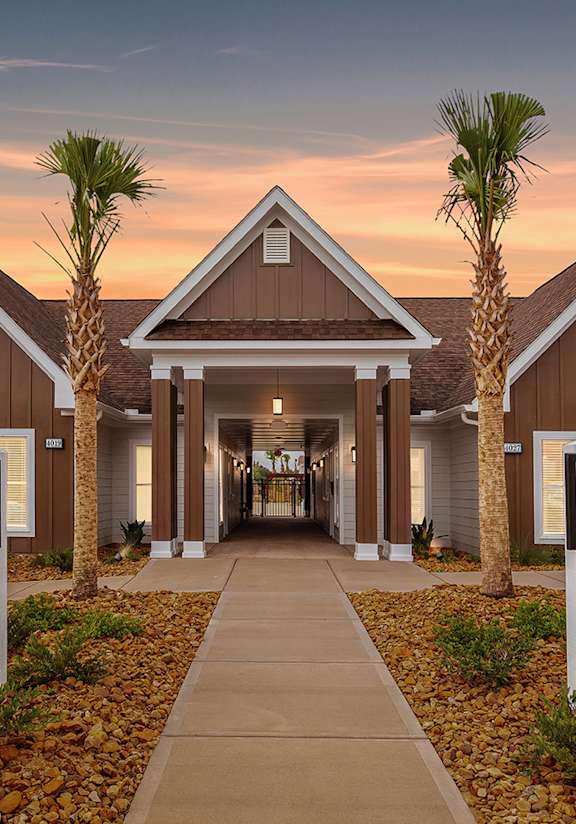 an empty street in front of a building with a sign on the side at The Vista Apartments & Townhomes, Warrenville, SC