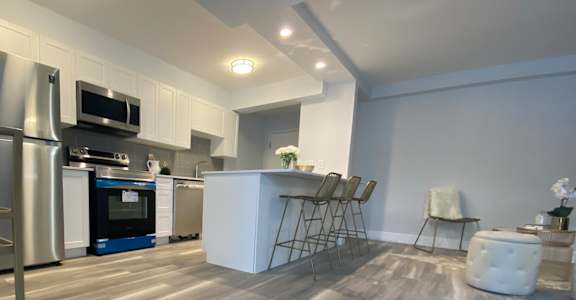 A modern kitchen with a wooden floor and white walls.