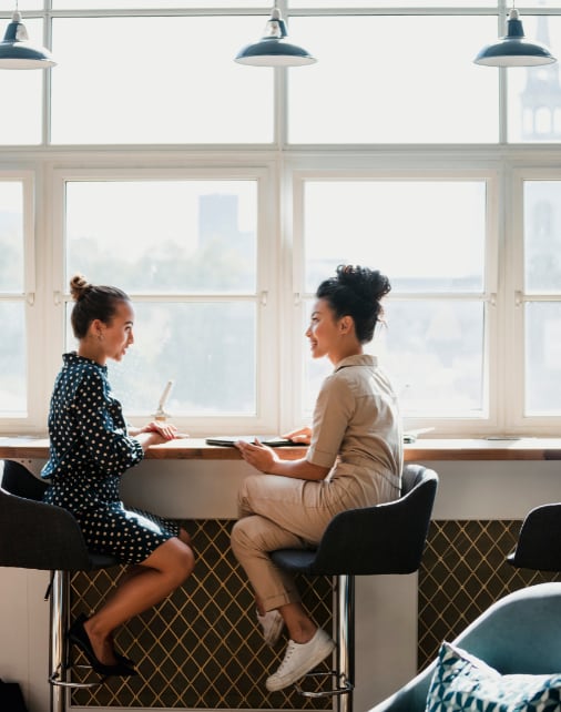two women sitting at a table in front of a window