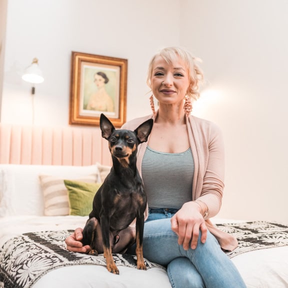 a woman sitting on a bed with her small dog