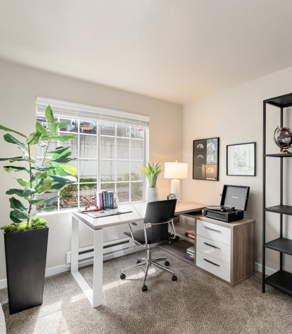 a bedroom with a desk and chair and a window