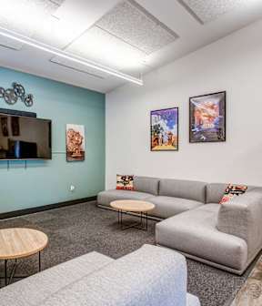 A living room with a grey couch, a wooden table, and a television.
