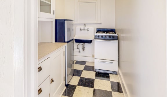 a small kitchen with white cabinets and a black and white checkered floor