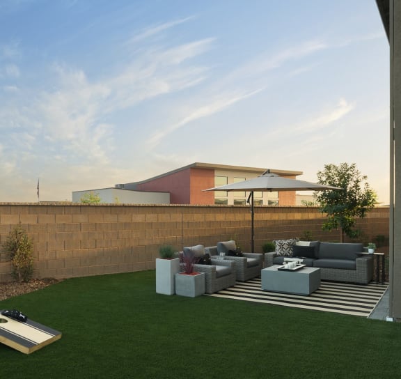 a yard with couches and a coffee table in front of a brick wall