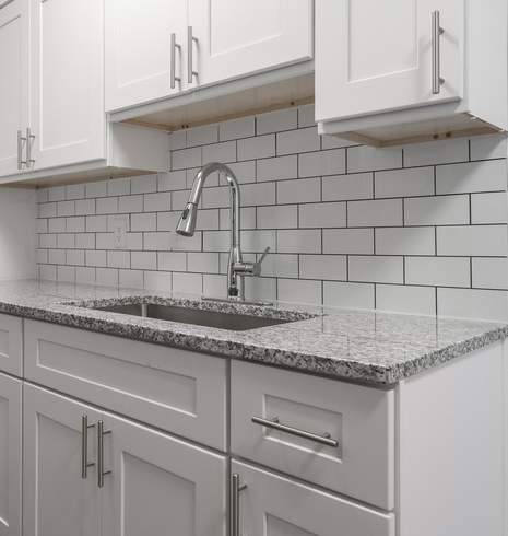 A kitchen with white cabinets and a black refrigerator.