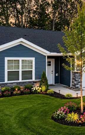 A blue house with a white garage door and a tree in the front yard.