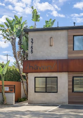 A two-story building with a garage door and a sign that says "For Rent".