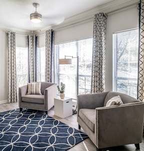 A living room with a grey couch, a grey armchair, a white side table, and a black and white rug. at Lincoln at Wolfchase Apartments, Cordova, 38016