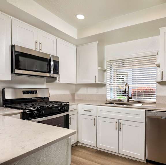 A kitchen with white cabinets and appliances.