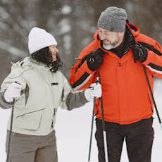 A man and a woman are standing in the snow with ski poles.