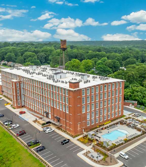 A large red brick building with a pool in front of it.