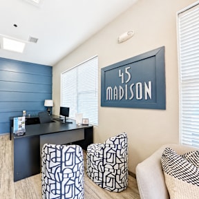A room with a desk, chairs and a window.