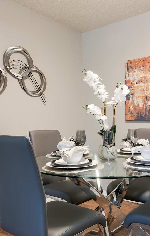 a dining room with a glass table and gray chairs