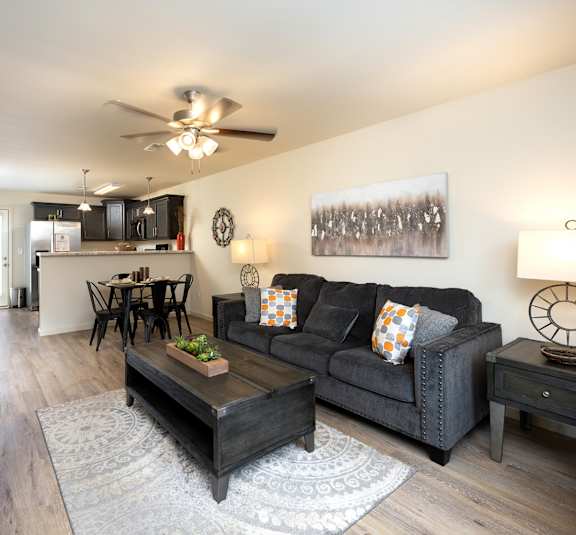 A living room with a couch, coffee table, and a ceiling fan.