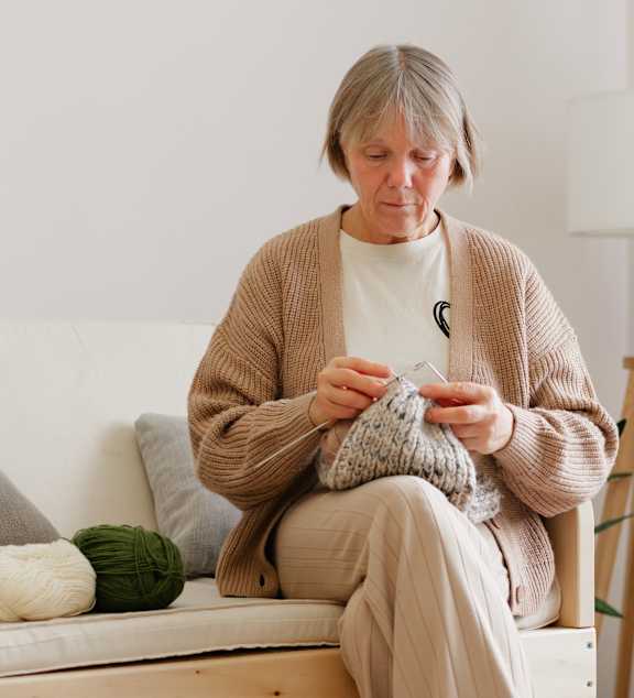 An older woman and a younger girl are sitting on a couch looking at a tablet.