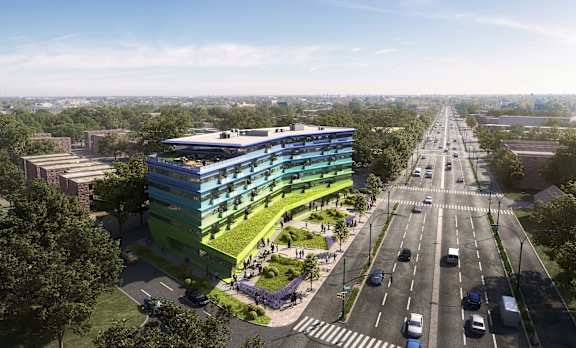 An aerial view of a modern building with a green roof and a street in front of it.
