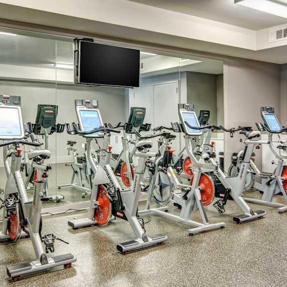 a room filled with lots of cardio equipment and a flat screen tv