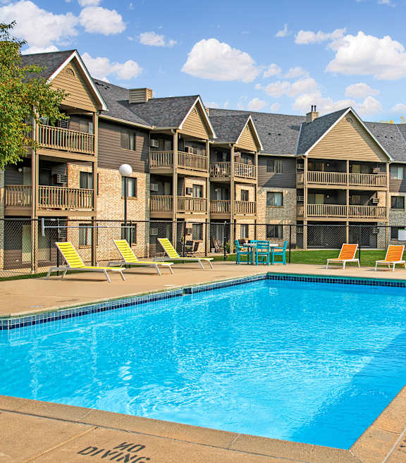 A large swimming pool in front of apartment buildings.