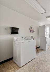 A laundry room with a washer and dryer, a chair, and a window.