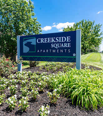 a sign for creekside square apartments in front of a flower garden at Creekside Square Apartments, Indianapolis, IN 46254