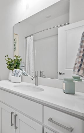 a white bathroom with a white counter top and a glass shower