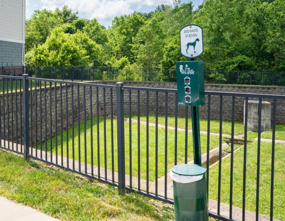 a black wrought iron fence with a green sign on it and a yard behind it