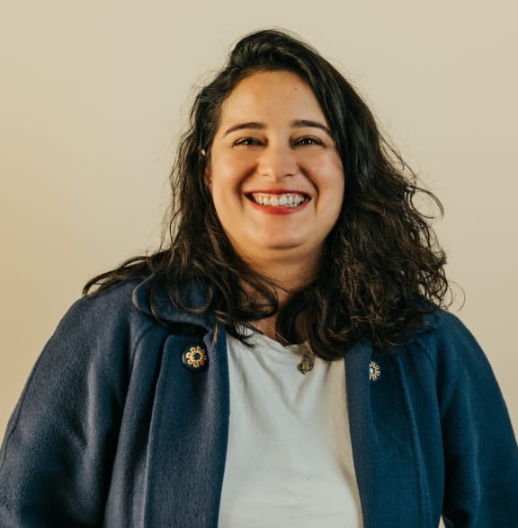 a smiling woman wearing a blue jacket and a white shirt