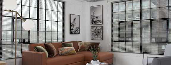 A living room with a brown couch, a black coffee table, and a large window with blinds.